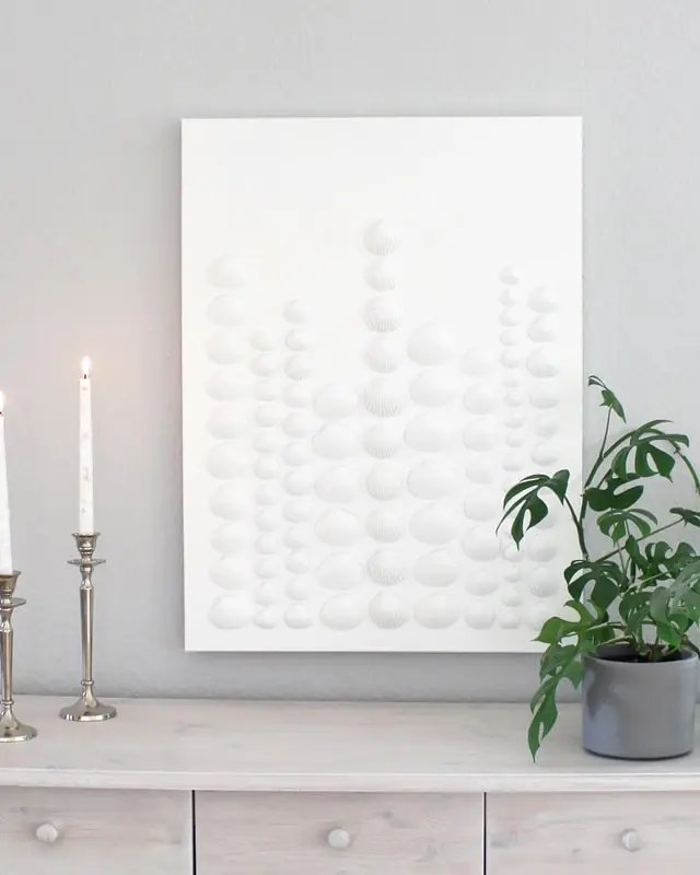 Sammelst du auch so gerne Muscheln? Damit diese nicht einfach in irgendeiner Kiste landen, habe ich ein DIY Bild mit Muscheln für meine Mama gebastelt. Dieses besteht aus Muscheln, die sie viele Jahre gesammelt hat. Das Tolle ist, dass man die Struktur der Muscheln auch nach dem Ansprühen noch erkennt und dadurch auch weiß, welche Muscheln wo gesammelt wurden. Das Bild wurde übrigens direkt zum Eyecatcher und ist allen sofort aufgefallen, obwohl es extra schlicht ist. Mittlerweile habe ich auch ein Muschelbild für uns gebastelt und dieses steht im Sommer bei uns im Wohnzimmer. Allerdings habe ich unser DIY Muschelbild spontan farblich anders gestaltet. DIY Bild mit Muscheln basteln - Muschelbild | Einfache DIYs für dein Zuhause