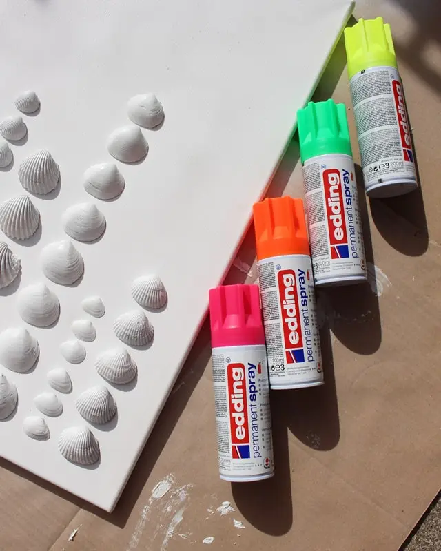 Sammelst du auch so gerne Muscheln? Damit diese nicht einfach in irgendeiner Kiste landen, habe ich ein DIY Bild mit Muscheln für meine Mama gebastelt. Dieses besteht aus Muscheln, die sie viele Jahre gesammelt hat. Das Tolle ist, dass man die Struktur der Muscheln auch nach dem Ansprühen noch erkennt und dadurch auch weiß, welche Muscheln wo gesammelt wurden. Das Bild wurde übrigens direkt zum Eyecatcher und ist allen sofort aufgefallen, obwohl es extra schlicht ist. Mittlerweile habe ich auch ein Muschelbild für uns gebastelt und dieses steht im Sommer bei uns im Wohnzimmer. Allerdings habe ich unser DIY Muschelbild spontan farblich anders gestaltet. Sommerliches DIY Bild mit Muscheln basteln - diy muschelbild neon 1