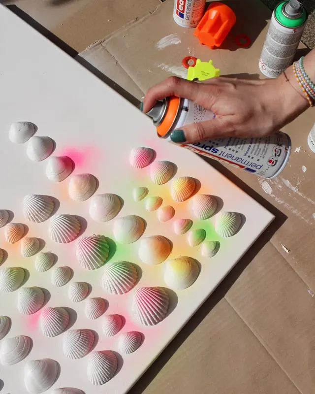 Sammelst du auch so gerne Muscheln? Damit diese nicht einfach in irgendeiner Kiste landen, habe ich ein DIY Bild mit Muscheln für meine Mama gebastelt. Dieses besteht aus Muscheln, die sie viele Jahre gesammelt hat. Das Tolle ist, dass man die Struktur der Muscheln auch nach dem Ansprühen noch erkennt und dadurch auch weiß, welche Muscheln wo gesammelt wurden. Das Bild wurde übrigens direkt zum Eyecatcher und ist allen sofort aufgefallen, obwohl es extra schlicht ist. Mittlerweile habe ich auch ein Muschelbild für uns gebastelt und dieses steht im Sommer bei uns im Wohnzimmer. Allerdings habe ich unser DIY Muschelbild spontan farblich anders gestaltet. Sommerliches DIY Bild mit Muscheln basteln - diy muschelbild neon 3