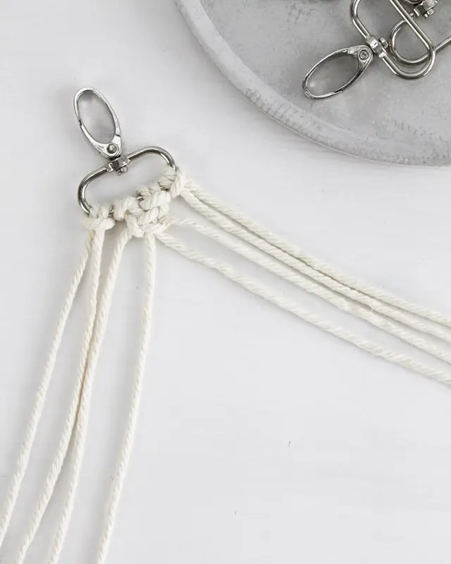 Makramee ist weiterhin im Trend und neben den klassischen Wandbehängen gibt es viele weitere Anwendungsmöglichkeiten. Im letzten Jahr habe ich mir sogar eine eigene Handtasche geknüpft. Vor ein paar Wochen bin ich nach Paris gereist und dafür brauchte ich eine kleine Umhängetasche, die ich gut vorne tragen kann. Parallel knüpfte ich an einem anderen Makrameeprojekt: einem Makramee-Übertopf mit dickerem Makrameegarn. Dabei kam mir die Idee, dass ein DIY Makramee Schultergurt aus diesem dicken Makrameegarn sicherlich toll aussähe. Also habe ich mich auf die Suche nach einer passenden Umhängetasche begeben, bei der ich den Schultergurt einfach abmachen kann, um später meinen eigenen Makramee Schultergurt daran zu befestigen. So kann man die Schultergurte beliebig wechseln. DIY Makramee Schultergurt knüpfen - 4 Anleitungen - diy makramee schultergurt handtasche knuepfen 12