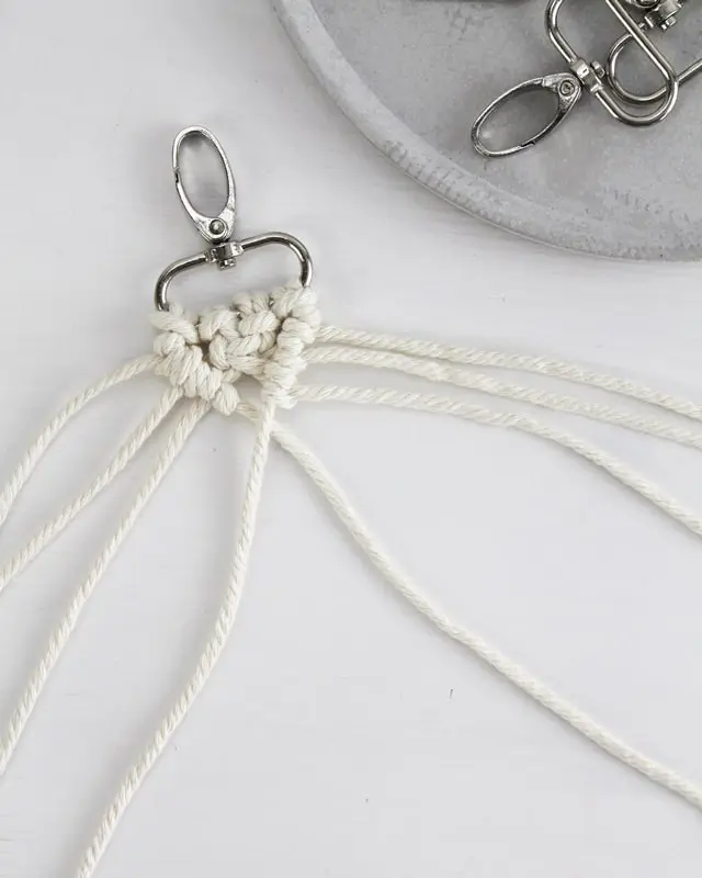 Makramee ist weiterhin im Trend und neben den klassischen Wandbehängen gibt es viele weitere Anwendungsmöglichkeiten. Im letzten Jahr habe ich mir sogar eine eigene Handtasche geknüpft. Vor ein paar Wochen bin ich nach Paris gereist und dafür brauchte ich eine kleine Umhängetasche, die ich gut vorne tragen kann. Parallel knüpfte ich an einem anderen Makrameeprojekt: einem Makramee-Übertopf mit dickerem Makrameegarn. Dabei kam mir die Idee, dass ein DIY Makramee Schultergurt aus diesem dicken Makrameegarn sicherlich toll aussähe. Also habe ich mich auf die Suche nach einer passenden Umhängetasche begeben, bei der ich den Schultergurt einfach abmachen kann, um später meinen eigenen Makramee Schultergurt daran zu befestigen. So kann man die Schultergurte beliebig wechseln. DIY Makramee Schultergurt knüpfen - 4 Anleitungen - diy makramee schultergurt handtasche knuepfen 31