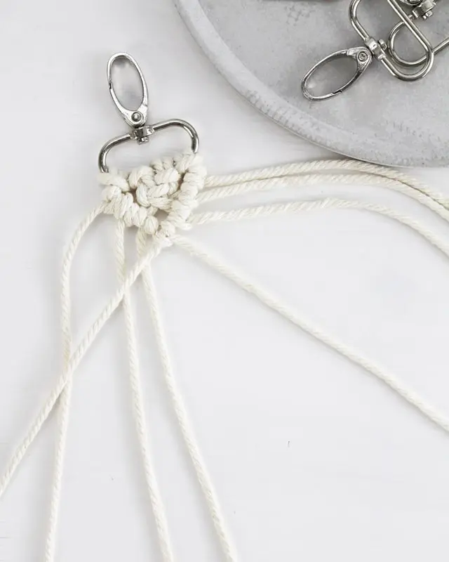 Makramee ist weiterhin im Trend und neben den klassischen Wandbehängen gibt es viele weitere Anwendungsmöglichkeiten. Im letzten Jahr habe ich mir sogar eine eigene Handtasche geknüpft. Vor ein paar Wochen bin ich nach Paris gereist und dafür brauchte ich eine kleine Umhängetasche, die ich gut vorne tragen kann. Parallel knüpfte ich an einem anderen Makrameeprojekt: einem Makramee-Übertopf mit dickerem Makrameegarn. Dabei kam mir die Idee, dass ein DIY Makramee Schultergurt aus diesem dicken Makrameegarn sicherlich toll aussähe. Also habe ich mich auf die Suche nach einer passenden Umhängetasche begeben, bei der ich den Schultergurt einfach abmachen kann, um später meinen eigenen Makramee Schultergurt daran zu befestigen. So kann man die Schultergurte beliebig wechseln. DIY Makramee Schultergurt knüpfen - 4 Anleitungen - diy makramee schultergurt handtasche knuepfen 35