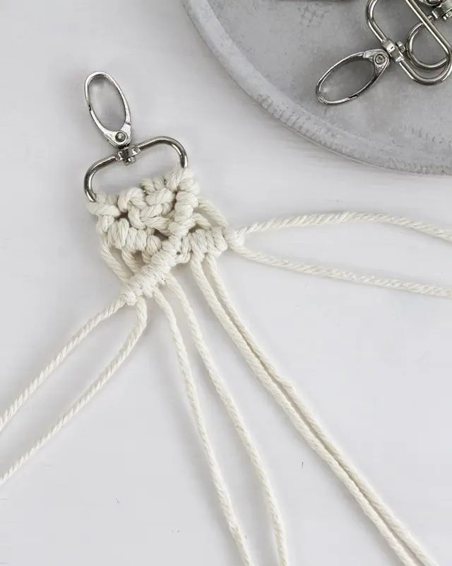 Makramee ist weiterhin im Trend und neben den klassischen Wandbehängen gibt es viele weitere Anwendungsmöglichkeiten. Im letzten Jahr habe ich mir sogar eine eigene Handtasche geknüpft. Vor ein paar Wochen bin ich nach Paris gereist und dafür brauchte ich eine kleine Umhängetasche, die ich gut vorne tragen kann. Parallel knüpfte ich an einem anderen Makrameeprojekt: einem Makramee-Übertopf mit dickerem Makrameegarn. Dabei kam mir die Idee, dass ein DIY Makramee Schultergurt aus diesem dicken Makrameegarn sicherlich toll aussähe. Also habe ich mich auf die Suche nach einer passenden Umhängetasche begeben, bei der ich den Schultergurt einfach abmachen kann, um später meinen eigenen Makramee Schultergurt daran zu befestigen. So kann man die Schultergurte beliebig wechseln. DIY Makramee Schultergurt knüpfen - 4 Anleitungen - diy makramee schultergurt handtasche knuepfen 38