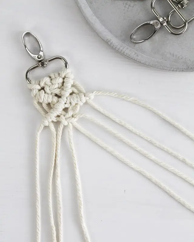 Makramee ist weiterhin im Trend und neben den klassischen Wandbehängen gibt es viele weitere Anwendungsmöglichkeiten. Im letzten Jahr habe ich mir sogar eine eigene Handtasche geknüpft. Vor ein paar Wochen bin ich nach Paris gereist und dafür brauchte ich eine kleine Umhängetasche, die ich gut vorne tragen kann. Parallel knüpfte ich an einem anderen Makrameeprojekt: einem Makramee-Übertopf mit dickerem Makrameegarn. Dabei kam mir die Idee, dass ein DIY Makramee Schultergurt aus diesem dicken Makrameegarn sicherlich toll aussähe. Also habe ich mich auf die Suche nach einer passenden Umhängetasche begeben, bei der ich den Schultergurt einfach abmachen kann, um später meinen eigenen Makramee Schultergurt daran zu befestigen. So kann man die Schultergurte beliebig wechseln. DIY Makramee Schultergurt knüpfen - 4 Anleitungen - diy makramee schultergurt handtasche knuepfen 39