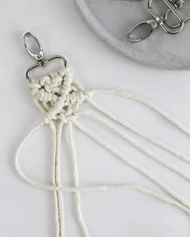 Makramee ist weiterhin im Trend und neben den klassischen Wandbehängen gibt es viele weitere Anwendungsmöglichkeiten. Im letzten Jahr habe ich mir sogar eine eigene Handtasche geknüpft. Vor ein paar Wochen bin ich nach Paris gereist und dafür brauchte ich eine kleine Umhängetasche, die ich gut vorne tragen kann. Parallel knüpfte ich an einem anderen Makrameeprojekt: einem Makramee-Übertopf mit dickerem Makrameegarn. Dabei kam mir die Idee, dass ein DIY Makramee Schultergurt aus diesem dicken Makrameegarn sicherlich toll aussähe. Also habe ich mich auf die Suche nach einer passenden Umhängetasche begeben, bei der ich den Schultergurt einfach abmachen kann, um später meinen eigenen Makramee Schultergurt daran zu befestigen. So kann man die Schultergurte beliebig wechseln. DIY Makramee Schultergurt knüpfen - 4 Anleitungen - diy makramee schultergurt handtasche knuepfen 40