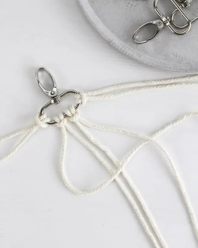 Makramee ist weiterhin im Trend und neben den klassischen Wandbehängen gibt es viele weitere Anwendungsmöglichkeiten. Im letzten Jahr habe ich mir sogar eine eigene Handtasche geknüpft. Vor ein paar Wochen bin ich nach Paris gereist und dafür brauchte ich eine kleine Umhängetasche, die ich gut vorne tragen kann. Parallel knüpfte ich an einem anderen Makrameeprojekt: einem Makramee-Übertopf mit dickerem Makrameegarn. Dabei kam mir die Idee, dass ein DIY Makramee Schultergurt aus diesem dicken Makrameegarn sicherlich toll aussähe. Also habe ich mich auf die Suche nach einer passenden Umhängetasche begeben, bei der ich den Schultergurt einfach abmachen kann, um später meinen eigenen Makramee Schultergurt daran zu befestigen. So kann man die Schultergurte beliebig wechseln. DIY Makramee Schultergurt knüpfen - 4 Anleitungen - diy makramee schultergurt handtasche knuepfen 5