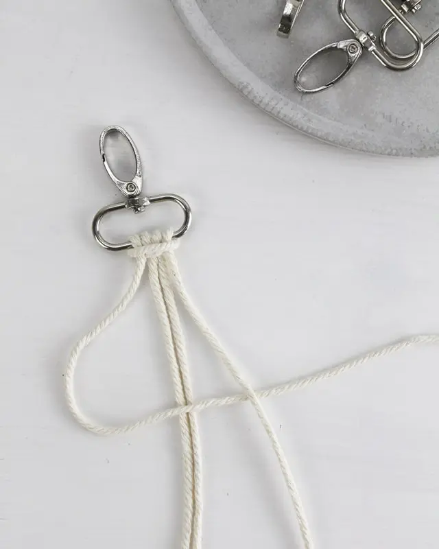 Makramee ist weiterhin im Trend und neben den klassischen Wandbehängen gibt es viele weitere Anwendungsmöglichkeiten. Im letzten Jahr habe ich mir sogar eine eigene Handtasche geknüpft. Vor ein paar Wochen bin ich nach Paris gereist und dafür brauchte ich eine kleine Umhängetasche, die ich gut vorne tragen kann. Parallel knüpfte ich an einem anderen Makrameeprojekt: einem Makramee-Übertopf mit dickerem Makrameegarn. Dabei kam mir die Idee, dass ein DIY Makramee Schultergurt aus diesem dicken Makrameegarn sicherlich toll aussähe. Also habe ich mich auf die Suche nach einer passenden Umhängetasche begeben, bei der ich den Schultergurt einfach abmachen kann, um später meinen eigenen Makramee Schultergurt daran zu befestigen. So kann man die Schultergurte beliebig wechseln. DIY Makramee Schultergurt knüpfen - 4 Anleitungen - diy makramee schultergurt handtasche knuepfen kreuzknoten 27