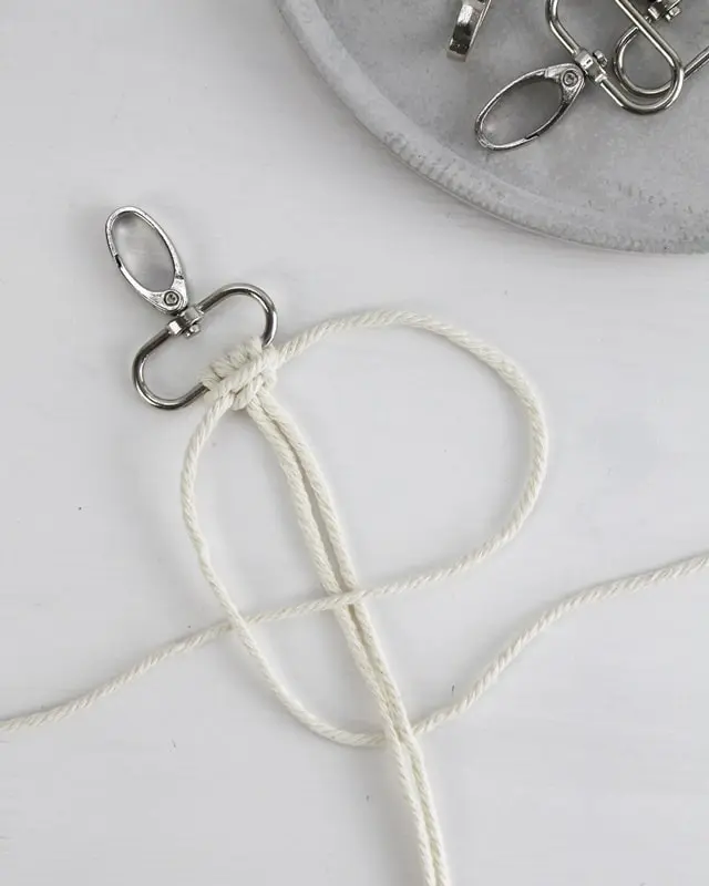 Makramee ist weiterhin im Trend und neben den klassischen Wandbehängen gibt es viele weitere Anwendungsmöglichkeiten. Im letzten Jahr habe ich mir sogar eine eigene Handtasche geknüpft. Vor ein paar Wochen bin ich nach Paris gereist und dafür brauchte ich eine kleine Umhängetasche, die ich gut vorne tragen kann. Parallel knüpfte ich an einem anderen Makrameeprojekt: einem Makramee-Übertopf mit dickerem Makrameegarn. Dabei kam mir die Idee, dass ein DIY Makramee Schultergurt aus diesem dicken Makrameegarn sicherlich toll aussähe. Also habe ich mich auf die Suche nach einer passenden Umhängetasche begeben, bei der ich den Schultergurt einfach abmachen kann, um später meinen eigenen Makramee Schultergurt daran zu befestigen. So kann man die Schultergurte beliebig wechseln. DIY Makramee Schultergurt knüpfen - 4 Anleitungen - diy makramee schultergurt handtasche knuepfen kreuzknoten 32