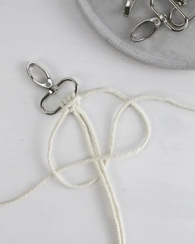 Makramee ist weiterhin im Trend und neben den klassischen Wandbehängen gibt es viele weitere Anwendungsmöglichkeiten. Im letzten Jahr habe ich mir sogar eine eigene Handtasche geknüpft. Vor ein paar Wochen bin ich nach Paris gereist und dafür brauchte ich eine kleine Umhängetasche, die ich gut vorne tragen kann. Parallel knüpfte ich an einem anderen Makrameeprojekt: einem Makramee-Übertopf mit dickerem Makrameegarn. Dabei kam mir die Idee, dass ein DIY Makramee Schultergurt aus diesem dicken Makrameegarn sicherlich toll aussähe. Also habe ich mich auf die Suche nach einer passenden Umhängetasche begeben, bei der ich den Schultergurt einfach abmachen kann, um später meinen eigenen Makramee Schultergurt daran zu befestigen. So kann man die Schultergurte beliebig wechseln. DIY Makramee Schultergurt knüpfen - 4 Anleitungen - diy makramee schultergurt handtasche knuepfen kreuzknoten 33