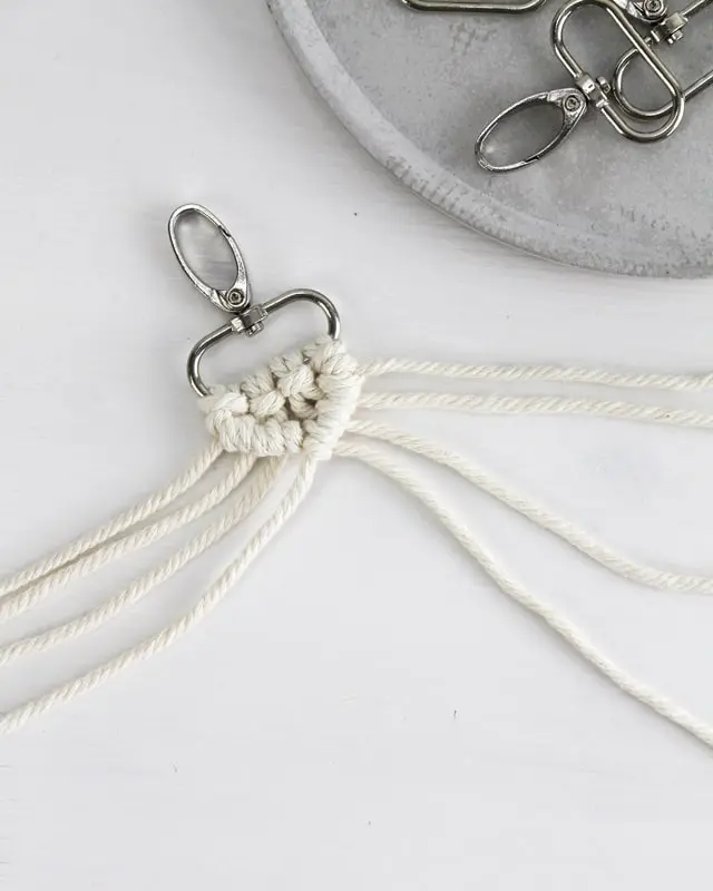 Makramee ist weiterhin im Trend und neben den klassischen Wandbehängen gibt es viele weitere Anwendungsmöglichkeiten. Im letzten Jahr habe ich mir sogar eine eigene Handtasche geknüpft. Vor ein paar Wochen bin ich nach Paris gereist und dafür brauchte ich eine kleine Umhängetasche, die ich gut vorne tragen kann. Parallel knüpfte ich an einem anderen Makrameeprojekt: einem Makramee-Übertopf mit dickerem Makrameegarn. Dabei kam mir die Idee, dass ein DIY Makramee Schultergurt aus diesem dicken Makrameegarn sicherlich toll aussähe. Also habe ich mich auf die Suche nach einer passenden Umhängetasche begeben, bei der ich den Schultergurt einfach abmachen kann, um später meinen eigenen Makramee Schultergurt daran zu befestigen. So kann man die Schultergurte beliebig wechseln. DIY Makramee Schultergurt knüpfen - 4 Anleitungen - diy makramee schultergurt handtasche knuepfen rippenknoten 17