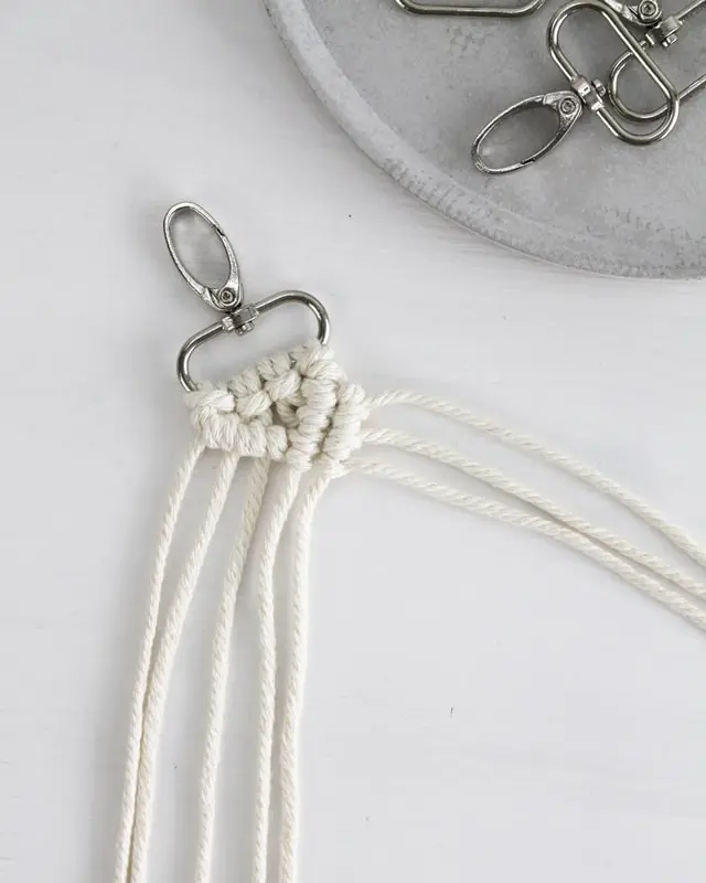 Makramee ist weiterhin im Trend und neben den klassischen Wandbehängen gibt es viele weitere Anwendungsmöglichkeiten. Im letzten Jahr habe ich mir sogar eine eigene Handtasche geknüpft. Vor ein paar Wochen bin ich nach Paris gereist und dafür brauchte ich eine kleine Umhängetasche, die ich gut vorne tragen kann. Parallel knüpfte ich an einem anderen Makrameeprojekt: einem Makramee-Übertopf mit dickerem Makrameegarn. Dabei kam mir die Idee, dass ein DIY Makramee Schultergurt aus diesem dicken Makrameegarn sicherlich toll aussähe. Also habe ich mich auf die Suche nach einer passenden Umhängetasche begeben, bei der ich den Schultergurt einfach abmachen kann, um später meinen eigenen Makramee Schultergurt daran zu befestigen. So kann man die Schultergurte beliebig wechseln. DIY Makramee Schultergurt knüpfen - 4 Anleitungen - diy makramee schultergurt handtasche knuepfen rippenknoten 19