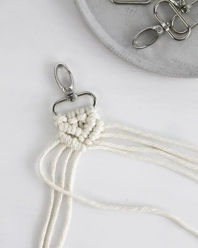 Makramee ist weiterhin im Trend und neben den klassischen Wandbehängen gibt es viele weitere Anwendungsmöglichkeiten. Im letzten Jahr habe ich mir sogar eine eigene Handtasche geknüpft. Vor ein paar Wochen bin ich nach Paris gereist und dafür brauchte ich eine kleine Umhängetasche, die ich gut vorne tragen kann. Parallel knüpfte ich an einem anderen Makrameeprojekt: einem Makramee-Übertopf mit dickerem Makrameegarn. Dabei kam mir die Idee, dass ein DIY Makramee Schultergurt aus diesem dicken Makrameegarn sicherlich toll aussähe. Also habe ich mich auf die Suche nach einer passenden Umhängetasche begeben, bei der ich den Schultergurt einfach abmachen kann, um später meinen eigenen Makramee Schultergurt daran zu befestigen. So kann man die Schultergurte beliebig wechseln. DIY Makramee Schultergurt knüpfen - 4 Anleitungen - diy makramee schultergurt handtasche knuepfen rippenknoten 22