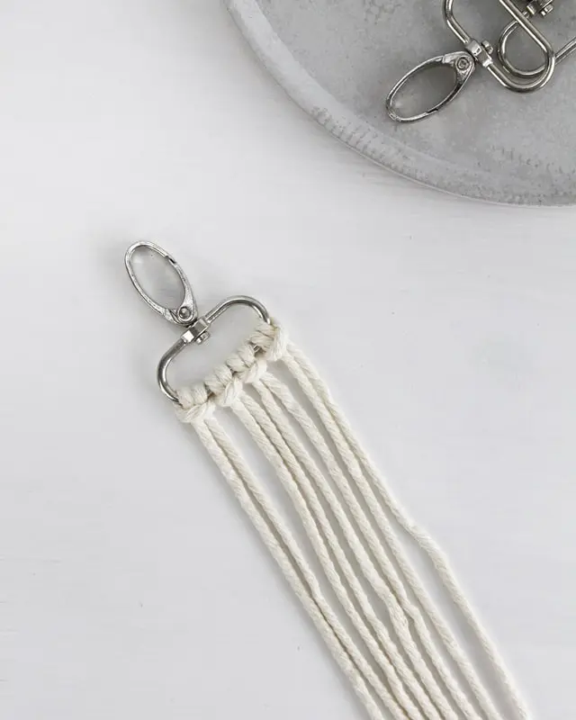 Makramee ist weiterhin im Trend und neben den klassischen Wandbehängen gibt es viele weitere Anwendungsmöglichkeiten. Im letzten Jahr habe ich mir sogar eine eigene Handtasche geknüpft. Vor ein paar Wochen bin ich nach Paris gereist und dafür brauchte ich eine kleine Umhängetasche, die ich gut vorne tragen kann. Parallel knüpfte ich an einem anderen Makrameeprojekt: einem Makramee-Übertopf mit dickerem Makrameegarn. Dabei kam mir die Idee, dass ein DIY Makramee Schultergurt aus diesem dicken Makrameegarn sicherlich toll aussähe. Also habe ich mich auf die Suche nach einer passenden Umhängetasche begeben, bei der ich den Schultergurt einfach abmachen kann, um später meinen eigenen Makramee Schultergurt daran zu befestigen. So kann man die Schultergurte beliebig wechseln. DIY Makramee Schultergurt knüpfen - 4 Anleitungen - diy schultergurt handtasche knuepfen kreuzknoten 1