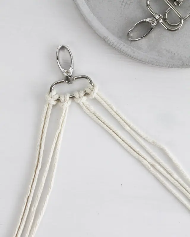 Makramee ist weiterhin im Trend und neben den klassischen Wandbehängen gibt es viele weitere Anwendungsmöglichkeiten. Im letzten Jahr habe ich mir sogar eine eigene Handtasche geknüpft. Vor ein paar Wochen bin ich nach Paris gereist und dafür brauchte ich eine kleine Umhängetasche, die ich gut vorne tragen kann. Parallel knüpfte ich an einem anderen Makrameeprojekt: einem Makramee-Übertopf mit dickerem Makrameegarn. Dabei kam mir die Idee, dass ein DIY Makramee Schultergurt aus diesem dicken Makrameegarn sicherlich toll aussähe. Also habe ich mich auf die Suche nach einer passenden Umhängetasche begeben, bei der ich den Schultergurt einfach abmachen kann, um später meinen eigenen Makramee Schultergurt daran zu befestigen. So kann man die Schultergurte beliebig wechseln. DIY Makramee Schultergurt knüpfen - 4 Anleitungen - diy schultergurt handtasche knuepfen kreuzknoten 2