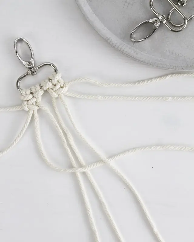 Makramee ist weiterhin im Trend und neben den klassischen Wandbehängen gibt es viele weitere Anwendungsmöglichkeiten. Im letzten Jahr habe ich mir sogar eine eigene Handtasche geknüpft. Vor ein paar Wochen bin ich nach Paris gereist und dafür brauchte ich eine kleine Umhängetasche, die ich gut vorne tragen kann. Parallel knüpfte ich an einem anderen Makrameeprojekt: einem Makramee-Übertopf mit dickerem Makrameegarn. Dabei kam mir die Idee, dass ein DIY Makramee Schultergurt aus diesem dicken Makrameegarn sicherlich toll aussähe. Also habe ich mich auf die Suche nach einer passenden Umhängetasche begeben, bei der ich den Schultergurt einfach abmachen kann, um später meinen eigenen Makramee Schultergurt daran zu befestigen. So kann man die Schultergurte beliebig wechseln. DIY Makramee Schultergurt knüpfen - 4 Anleitungen - diy schultergurt handtasche knuepfen kreuzknoten 20