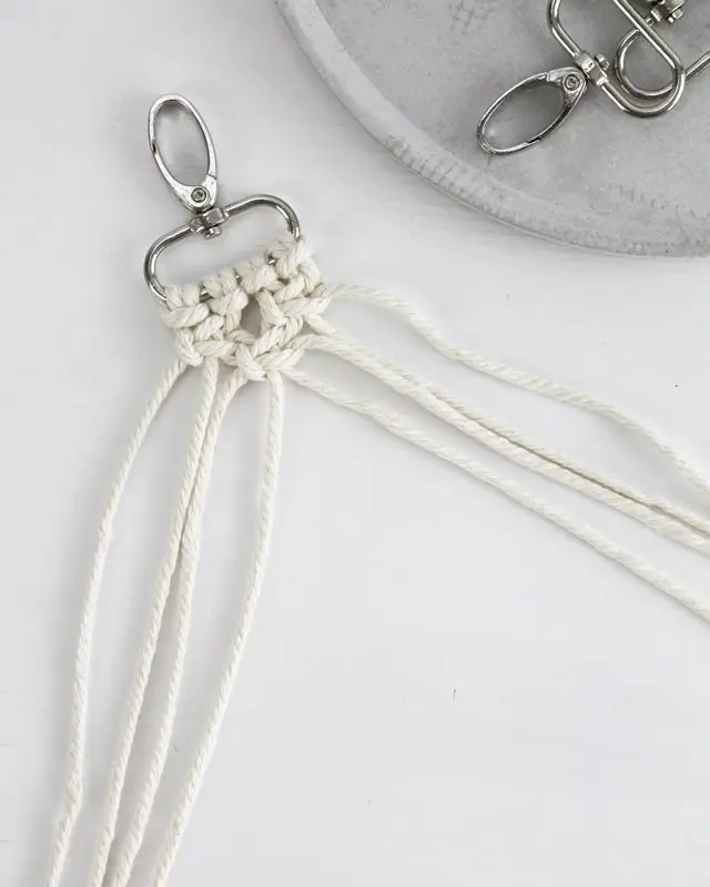 Makramee ist weiterhin im Trend und neben den klassischen Wandbehängen gibt es viele weitere Anwendungsmöglichkeiten. Im letzten Jahr habe ich mir sogar eine eigene Handtasche geknüpft. Vor ein paar Wochen bin ich nach Paris gereist und dafür brauchte ich eine kleine Umhängetasche, die ich gut vorne tragen kann. Parallel knüpfte ich an einem anderen Makrameeprojekt: einem Makramee-Übertopf mit dickerem Makrameegarn. Dabei kam mir die Idee, dass ein DIY Makramee Schultergurt aus diesem dicken Makrameegarn sicherlich toll aussähe. Also habe ich mich auf die Suche nach einer passenden Umhängetasche begeben, bei der ich den Schultergurt einfach abmachen kann, um später meinen eigenen Makramee Schultergurt daran zu befestigen. So kann man die Schultergurte beliebig wechseln. DIY Makramee Schultergurt knüpfen - 4 Anleitungen - diy schultergurt handtasche knuepfen kreuzknoten 25