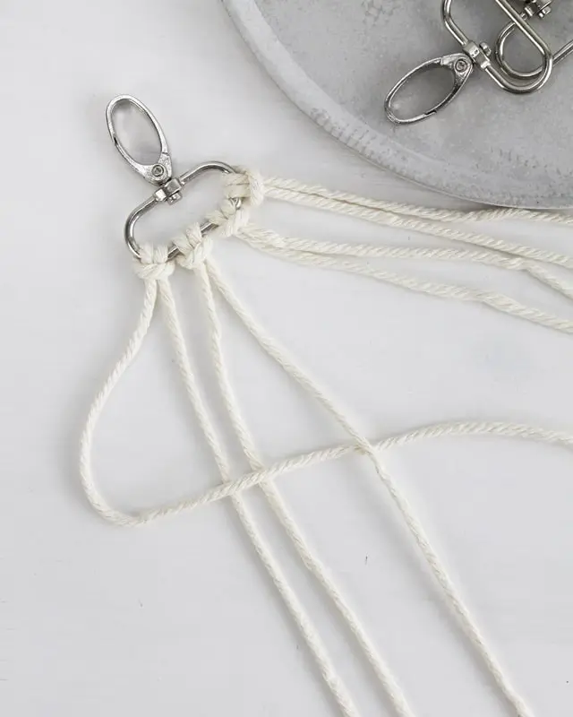 Makramee ist weiterhin im Trend und neben den klassischen Wandbehängen gibt es viele weitere Anwendungsmöglichkeiten. Im letzten Jahr habe ich mir sogar eine eigene Handtasche geknüpft. Vor ein paar Wochen bin ich nach Paris gereist und dafür brauchte ich eine kleine Umhängetasche, die ich gut vorne tragen kann. Parallel knüpfte ich an einem anderen Makrameeprojekt: einem Makramee-Übertopf mit dickerem Makrameegarn. Dabei kam mir die Idee, dass ein DIY Makramee Schultergurt aus diesem dicken Makrameegarn sicherlich toll aussähe. Also habe ich mich auf die Suche nach einer passenden Umhängetasche begeben, bei der ich den Schultergurt einfach abmachen kann, um später meinen eigenen Makramee Schultergurt daran zu befestigen. So kann man die Schultergurte beliebig wechseln. DIY Makramee Schultergurt knüpfen - 4 Anleitungen - diy schultergurt handtasche knuepfen kreuzknoten 3