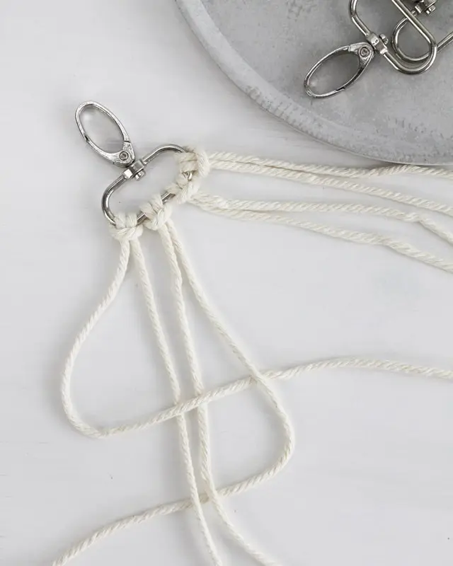 Makramee ist weiterhin im Trend und neben den klassischen Wandbehängen gibt es viele weitere Anwendungsmöglichkeiten. Im letzten Jahr habe ich mir sogar eine eigene Handtasche geknüpft. Vor ein paar Wochen bin ich nach Paris gereist und dafür brauchte ich eine kleine Umhängetasche, die ich gut vorne tragen kann. Parallel knüpfte ich an einem anderen Makrameeprojekt: einem Makramee-Übertopf mit dickerem Makrameegarn. Dabei kam mir die Idee, dass ein DIY Makramee Schultergurt aus diesem dicken Makrameegarn sicherlich toll aussähe. Also habe ich mich auf die Suche nach einer passenden Umhängetasche begeben, bei der ich den Schultergurt einfach abmachen kann, um später meinen eigenen Makramee Schultergurt daran zu befestigen. So kann man die Schultergurte beliebig wechseln. DIY Makramee Schultergurt knüpfen - 4 Anleitungen - diy schultergurt handtasche knuepfen kreuzknoten 4