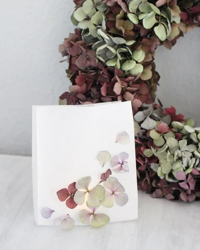 Auf Instagram werde ich von vielen als Windlicht-Queen bezeichnet und da ist es wohl langsam wirklich Zeit für einen Sammelbeitrag zum Thema DIY Windlichter zum Selbermachen. Um zu den Anleitungen zu gelangen, klicke einfach auf das Bild. Du wirst dann zu meinen Anleitungen auf dem Blog, YouTube und Instagram weitergeleitet. Zu manchen Windlichtern gibt es keine ausführliche Anleitung und deswegen steht unter den Bildern eine kurze Anleitung. Da ich aber auch einiges an Videocontent erstelle, gibt es zu manchen DIY Windlichtern sogar eine Videoanleitung, die ich im Blogbeitrag einbinden werde. So und jetzt wünsche ich dir viel Spaß beim Durchstöbern meiner Windlichtideen! Ideensammlung DIY Windlichter: Windlicht aus Papiertüte mit Hortensienblüten | Tinkerhome - Einfache DIYs für dein Zuhause