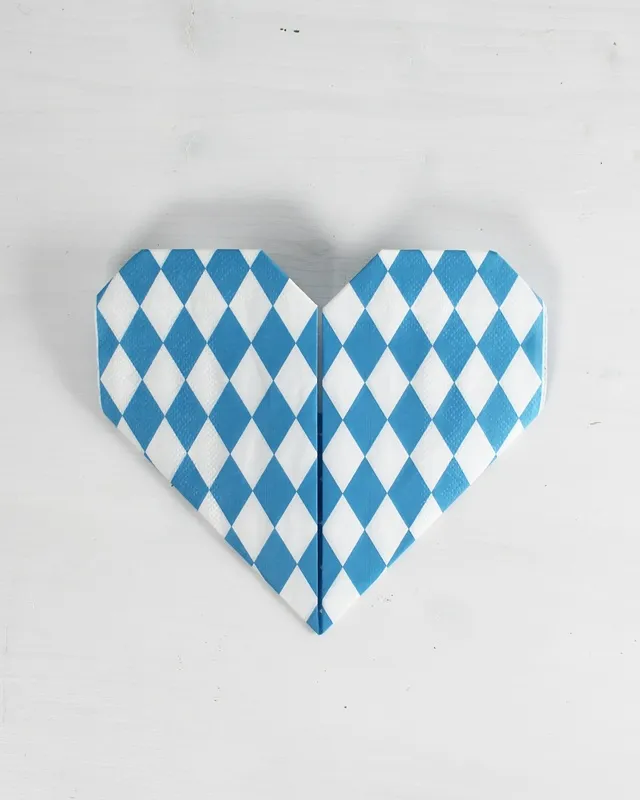 Statt kitschiger Plastikdeko kannst du deine Oktoberfest Tischdeko selber machen – rustikal, gemütlich und mit echtem Almcharakter. Viele greifen zwar schnell zu weiß-blauen Rauten und Einweg-Plastik, doch umwelttechnisch ist das kein Hit – und die Stimmung wirkt oft eher billig als festlich. Oktoberfest Tischdeko selber machen – 5 rustikale DIY Ideen im Almstil - servietten zu herzen falten 9