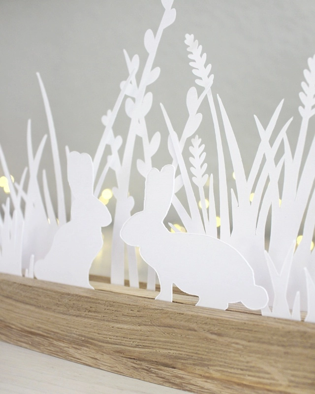 Gestalte mit der "Plotterdatei Osterwiese" eine schlichte Osterdeko aus Papier. Die minimalistischen Hasen- und Gräser-Motive können in Holzleisten oder auch als Fensterdeko genutzt werden. Plotterdateien (SVG + DXF) + PNG Plotterdatei Osterwiese - Minimalistische Osterdeko aus Papier plotten | Tinkerhome - Einfache DIYs für dein Zuhause