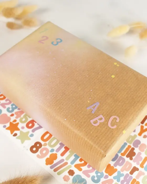 Die Einschulung steht vor der Tür und das perfekte Geschenk liegt bereit? Dann fehlt jetzt nur noch die passende Hülle! Wenn du eine Geschenkverpackung zur Einschulung basteln möchtest, die garantiert für leuchtende Augen sorgt, bist du hier genau richtig. Ich zeige dir, wie du einfaches Geschenkpapier aufpeppen oder aus ein paar Materialien eine ausgefallene Geschenkverpackung zur Einschulung basteln kannst. Geschenkverpackung zur Einschulung basteln: 3 kreative DIY-Ideen - geschenkverpackung einschulung basteln buchstabensticker 2